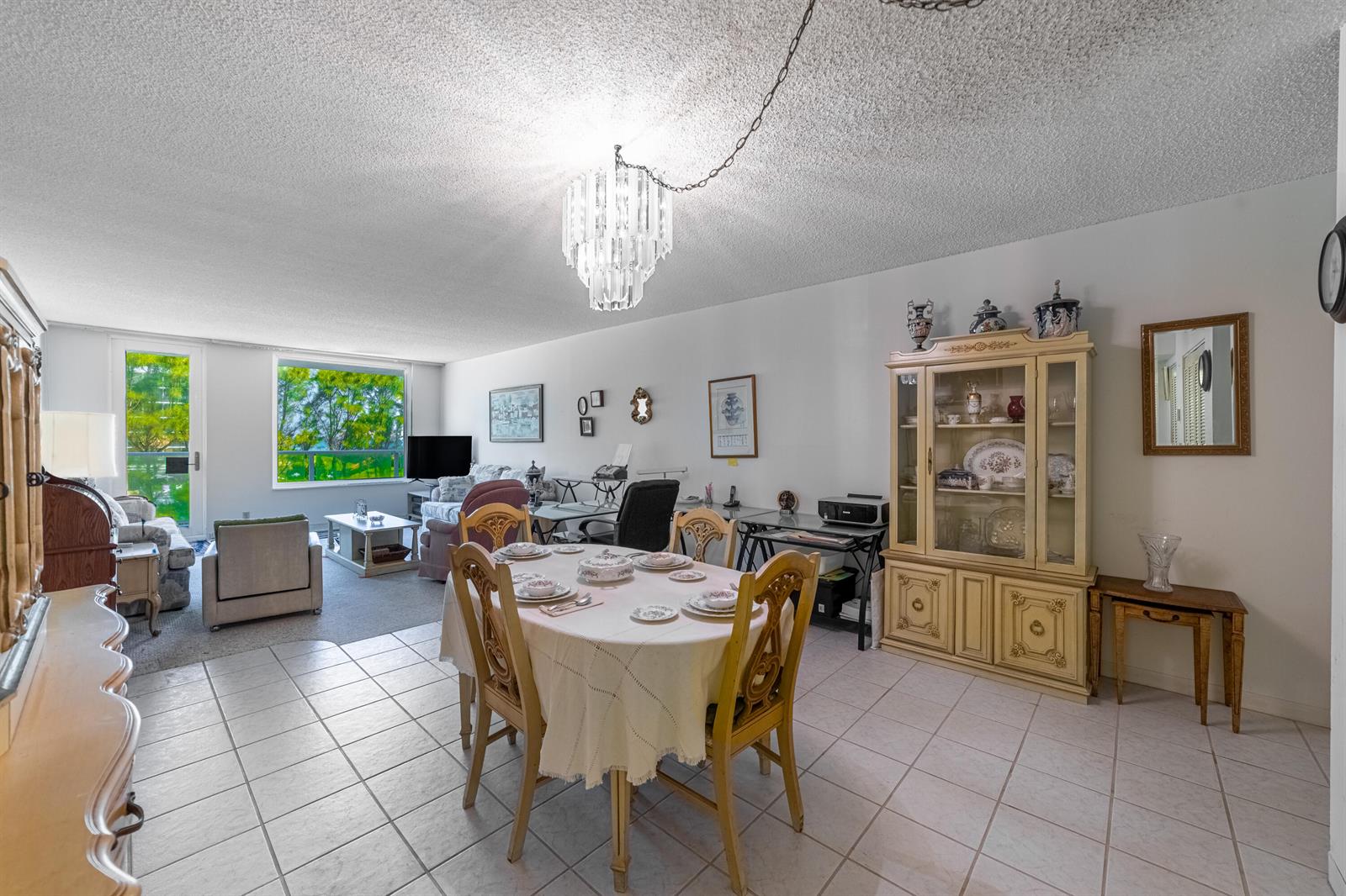 A dining area with a tiled floor and chandelier sits adjacent to a carpeted living room — 3450 S Ocean Boulevard # 206, Palm Beach FL 33480, PALM BEACH, FL