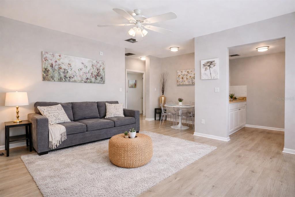 A living room with a gray sofa, round woven ottoman, and an adjacent dining area — 501 S MAGNOLIA AVENUE UNIT 4, TAMPA, FL