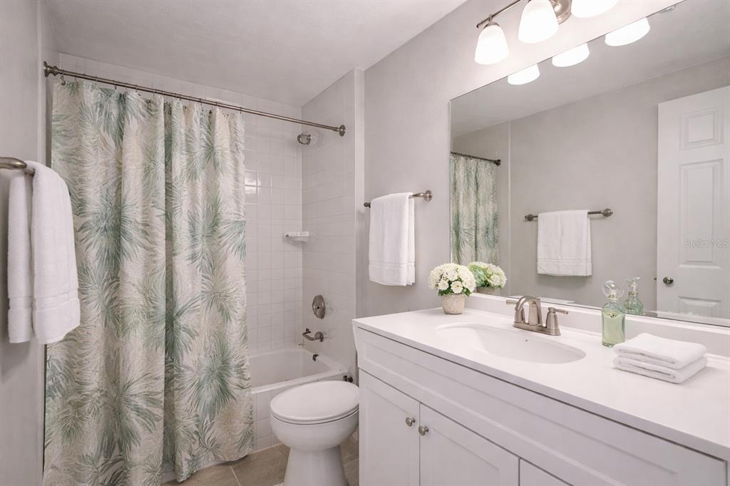 A bathroom features a white vanity, a toilet, and a shower-tub combination with a patterned curtain — 501 S MAGNOLIA AVENUE UNIT 4, TAMPA, FL