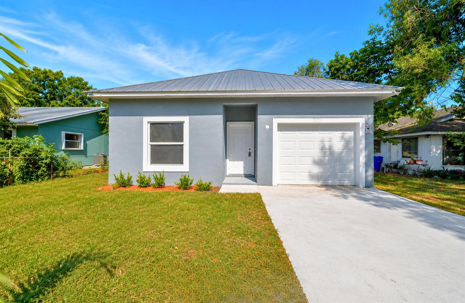 A gray single-story house with a metal roof, a white garage door, and a front lawn — 320 13th Street SW, Vero Beach FL 32962, VERO BEACH, FL
