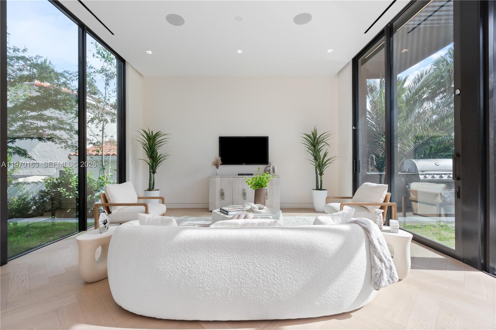 A modern living room features a curved white sofa, two armchairs, and floor-to-ceiling windows — 536 W 51st St, Miami Beach FL 33140, MIAMI BEACH, FL
