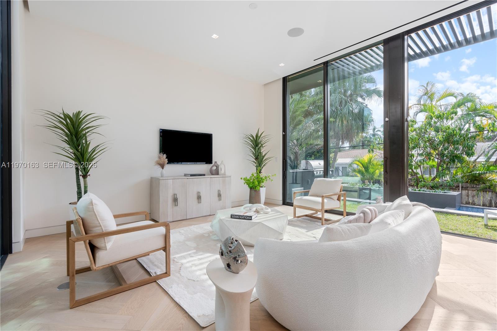 A modern living room features a curved sofa, two armchairs, and floor-to-ceiling glass doors — 536 W 51st St, Miami Beach FL 33140, MIAMI BEACH, FL