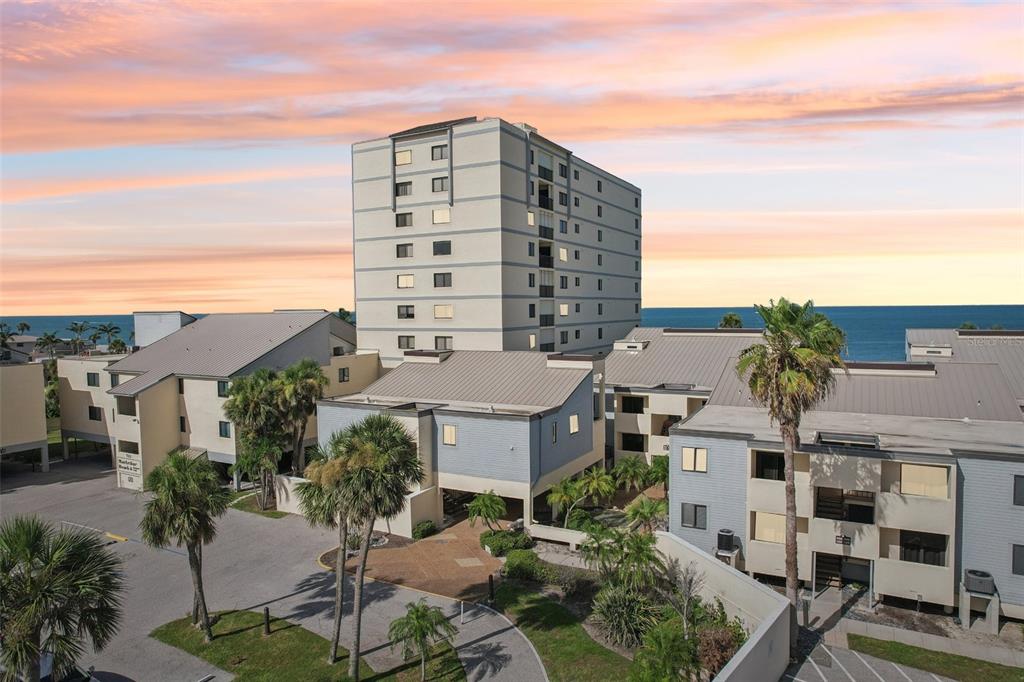 An aerial view shows a multi-story apartment building and surrounding complex near the ocean — 700 GOLDEN BEACH BOULEVARD UNIT 130, VENICE, FL