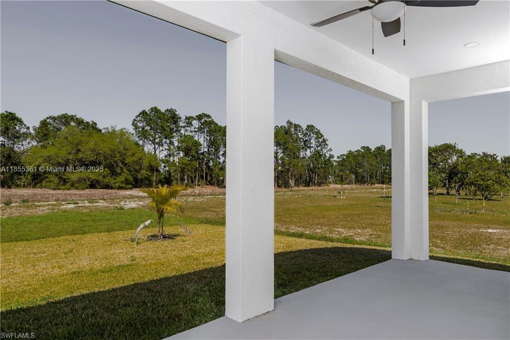 A covered patio with white columns overlooks a grassy field and a line of trees — 829 Gillian Ave, Lehigh Acres FL 33974, LEHIGH ACRES, FL