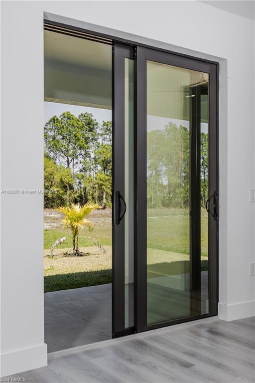 A sliding glass door opens to a patio with a view of trees and grass — 829 Gillian Ave, Lehigh Acres FL 33974, LEHIGH ACRES, FL
