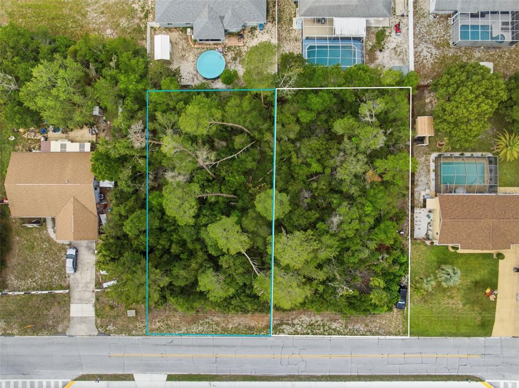 An aerial view shows two adjacent, wooded vacant lots situated between two residential properties — 6019 FREEPORT DRIVE, SPRING HILL, FL