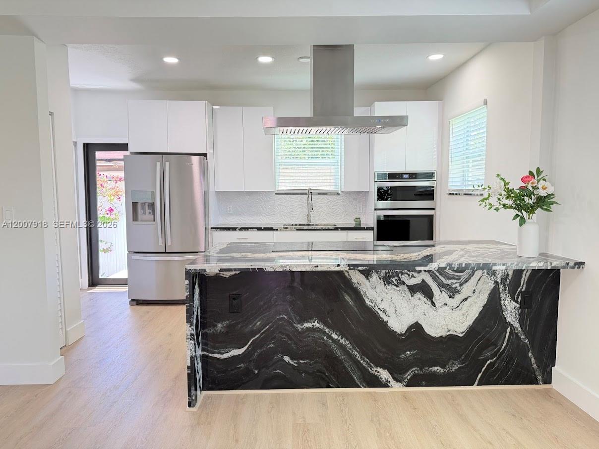 A modern kitchen features a large black and white marble waterfall island and stainless appliances — 2272 SW 13th St, Miami FL 33145, MIAMI, FL