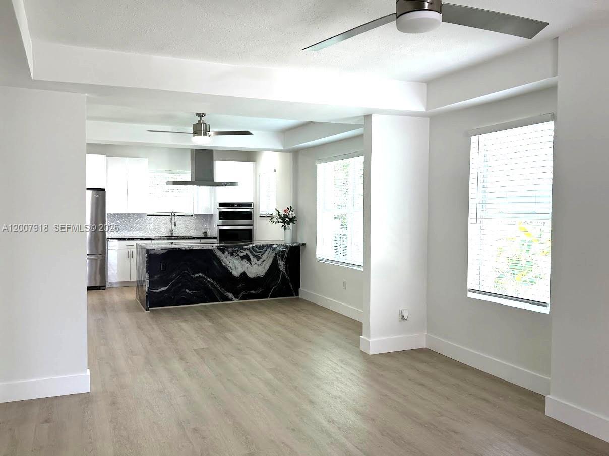 A kitchen with black marble counters and white cabinets opens into a living area — 2272 SW 13th St, Miami FL 33145, MIAMI, FL