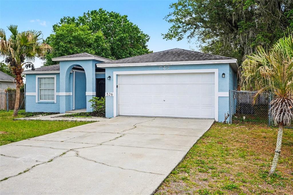 A light blue single-story house features a two-car garage, a covered entryway, and a driveway — 526 N FINCH COURT, KISSIMMEE, FL