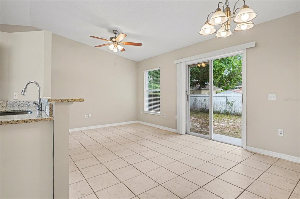 A dining area with tile floors, a ceiling fan, a chandelier, and sliding glass doors — 526 N FINCH COURT, KISSIMMEE, FL