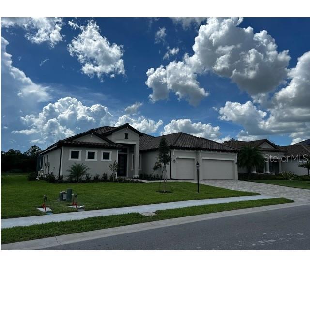 A single-story house with a light-colored stucco exterior, tile roof, and a two-car garage — 17021 POLO TRAIL, LAKEWOOD RANCH, FL