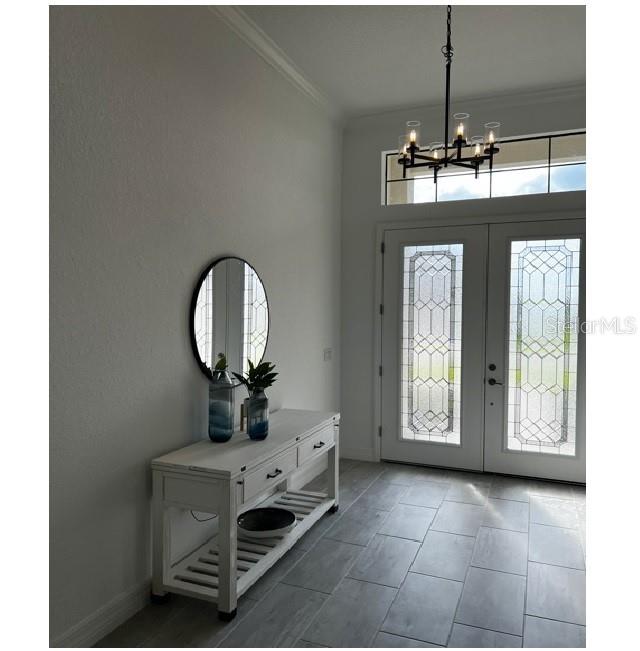 An entryway features a white console table, a round mirror, and a modern chandelier — 17021 POLO TRAIL, LAKEWOOD RANCH, FL