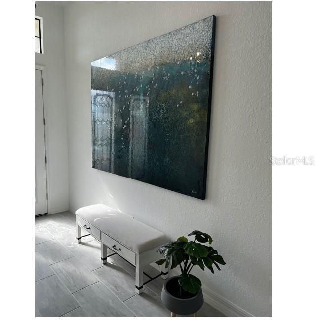 A white bench and a potted plant sit beneath a large abstract painting in a hallway — 17021 POLO TRAIL, LAKEWOOD RANCH, FL