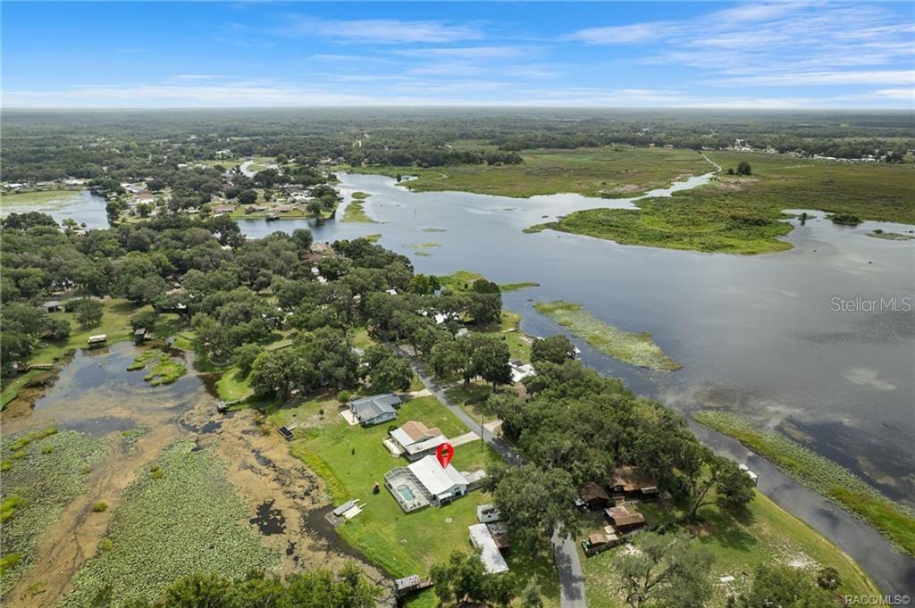 An aerial view shows a house with a pool located along a lakefront property — 8723 E AQUARIUS DRIVE, INVERNESS, FL