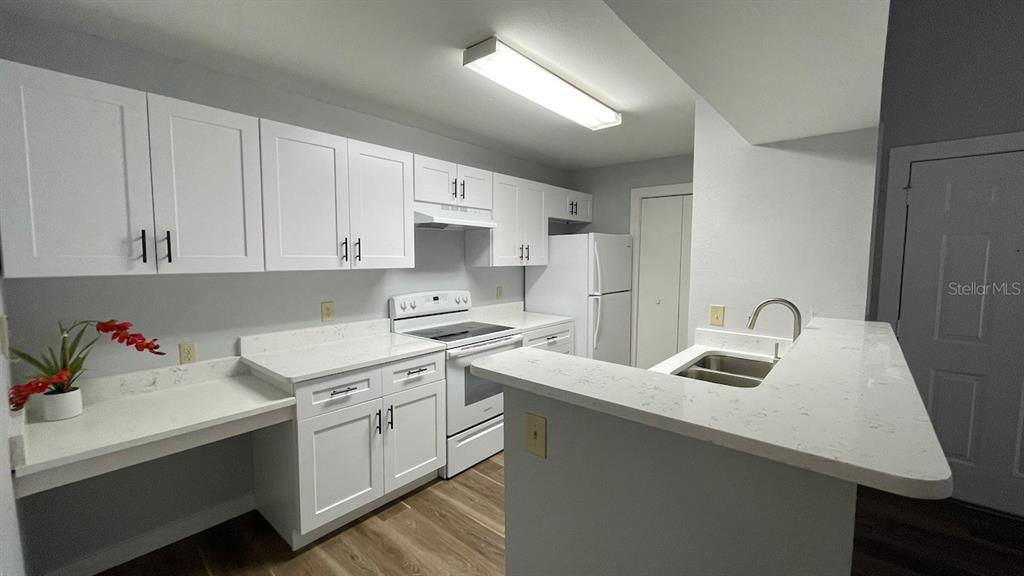 A kitchen features white cabinets, light countertops, stainless steel appliances, and a breakfast bar — 4225 THORNBRIAR LANE UNIT 201, ORLANDO, FL
