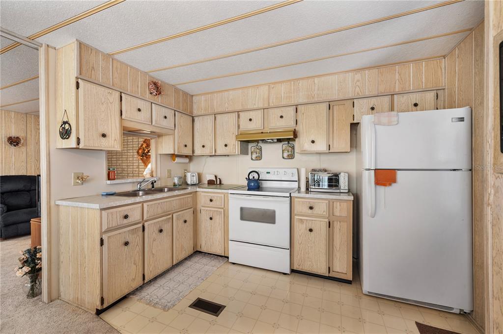 A kitchen features light wood cabinets, white appliances, and a tiled floor — 1610 REYNOLDS ROAD UNIT 262, LAKELAND, FL