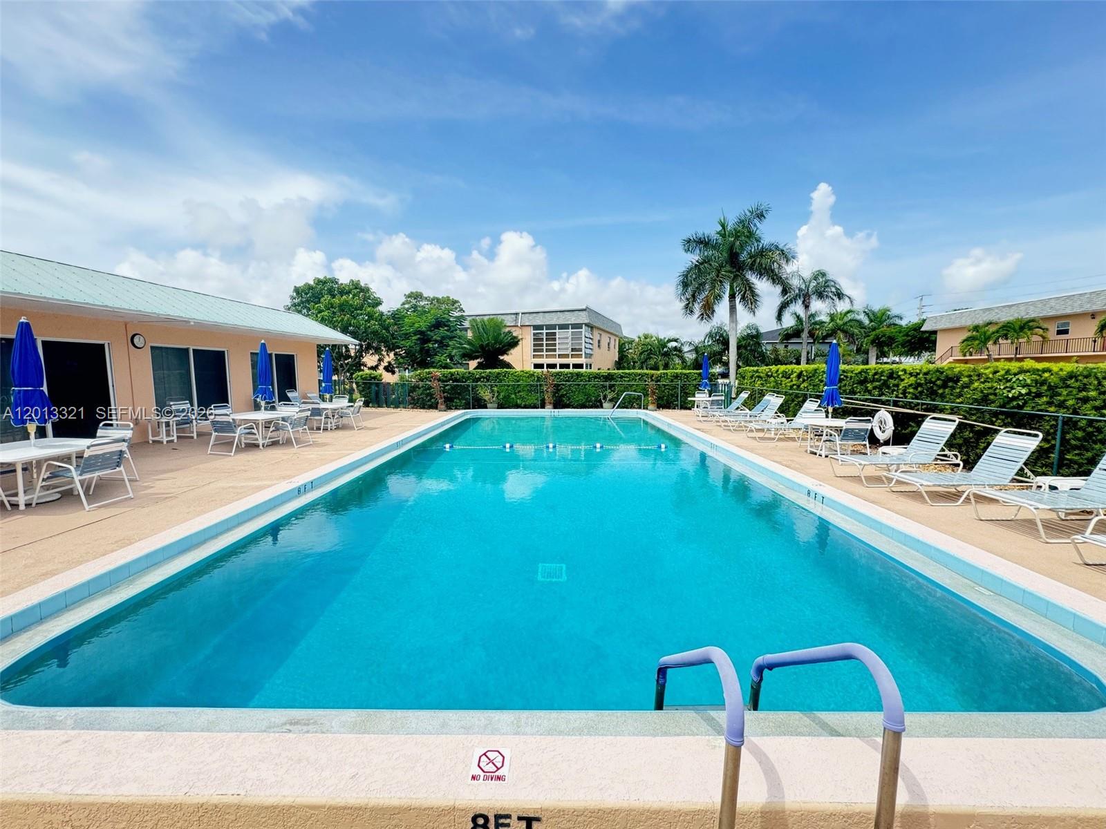 An outdoor swimming pool is surrounded by a concrete deck, lounge chairs, and palm trees — 2950 SE Ocean Blvd # 555, Stuart FL 34996, STUART, FL
