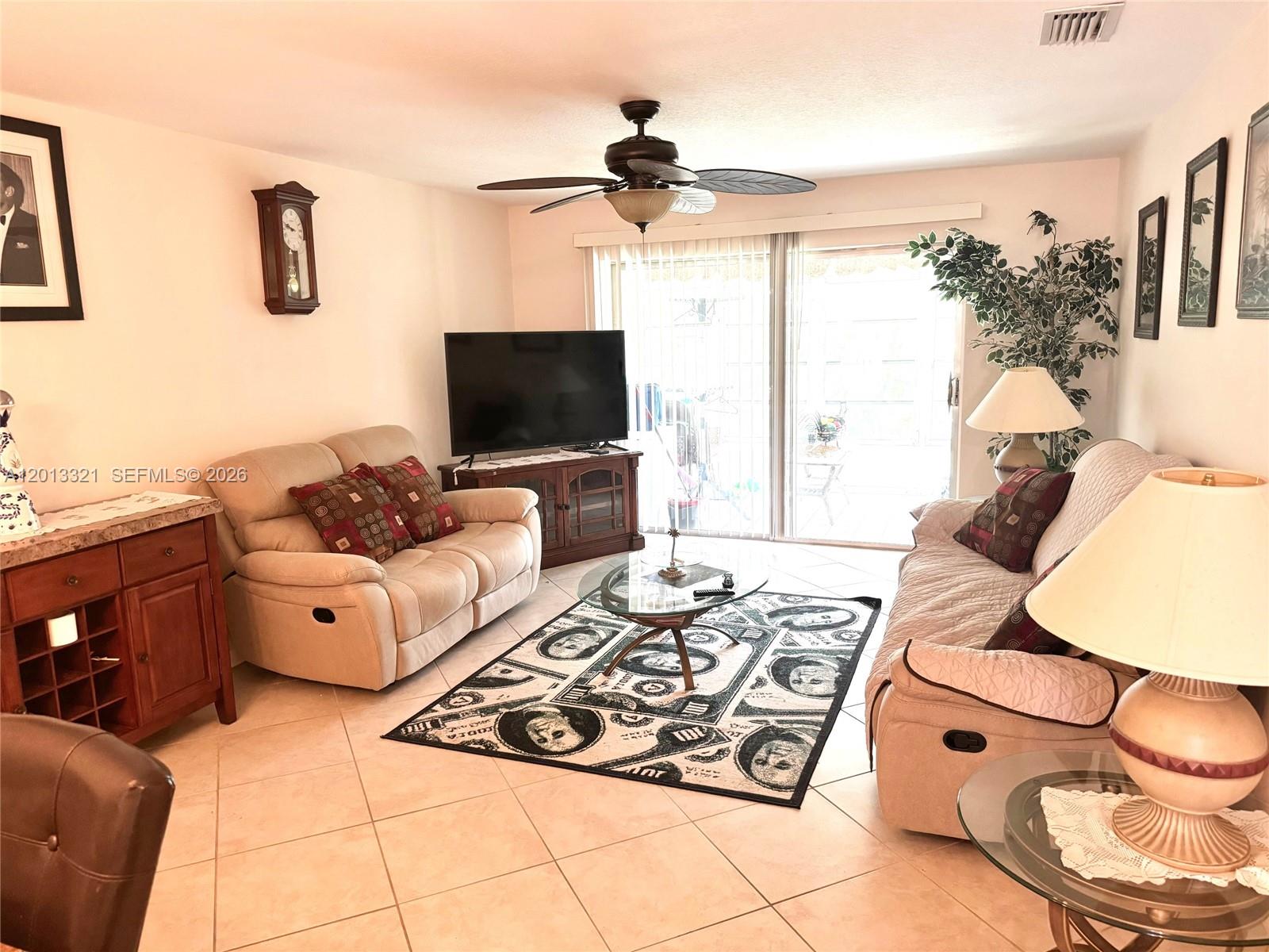 A living room features two beige sofas, a money-themed area rug, and a glass coffee table — 2950 SE Ocean Blvd # 555, Stuart FL 34996, STUART, FL