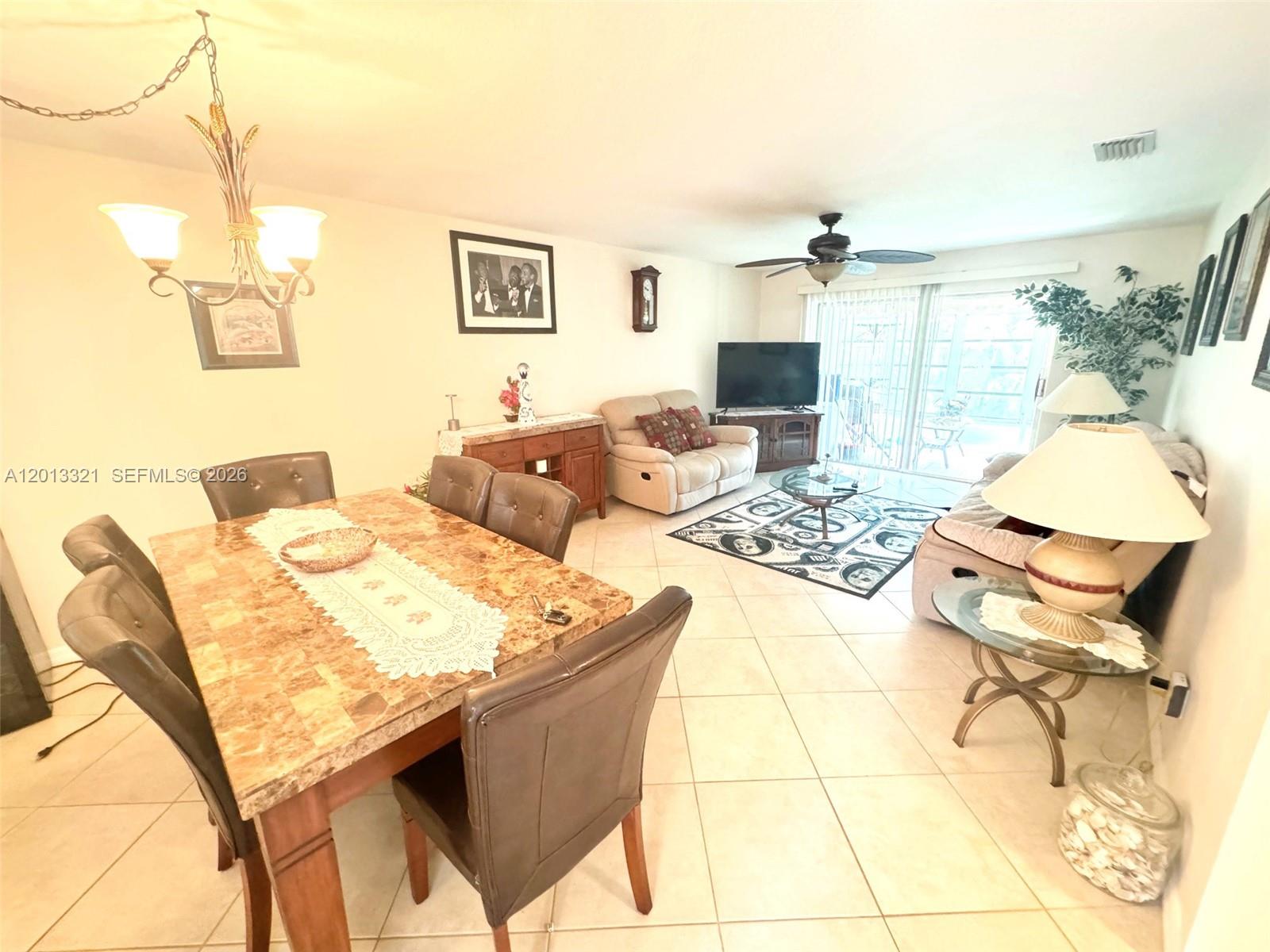 This open-concept living and dining area features tile flooring, a marble-topped table, and sliding doors — 2950 SE Ocean Blvd # 555, Stuart FL 34996, STUART, FL