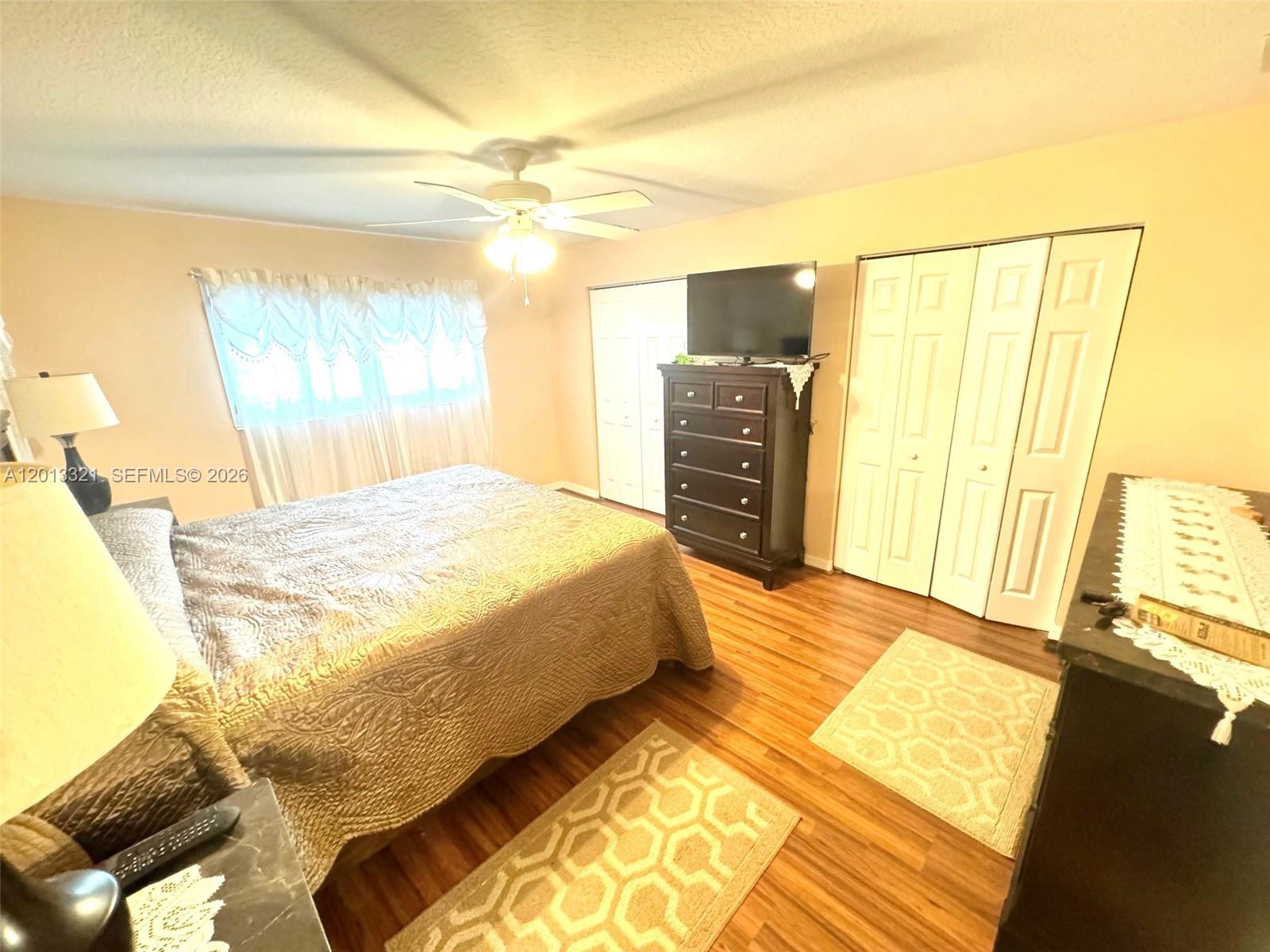 A bedroom features a bed, a dresser with a television, and two sets of closet doors — 2950 SE Ocean Blvd # 555, Stuart FL 34996, STUART, FL
