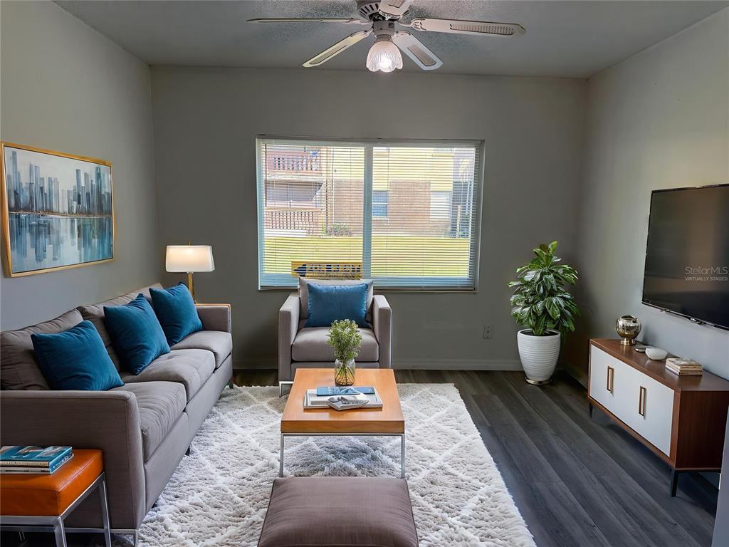 A living room features a gray sofa, armchair, wood coffee table, and a wall-mounted television — 9013 WESTCHESTER CIRCLE UNIT 32, TAMPA, FL