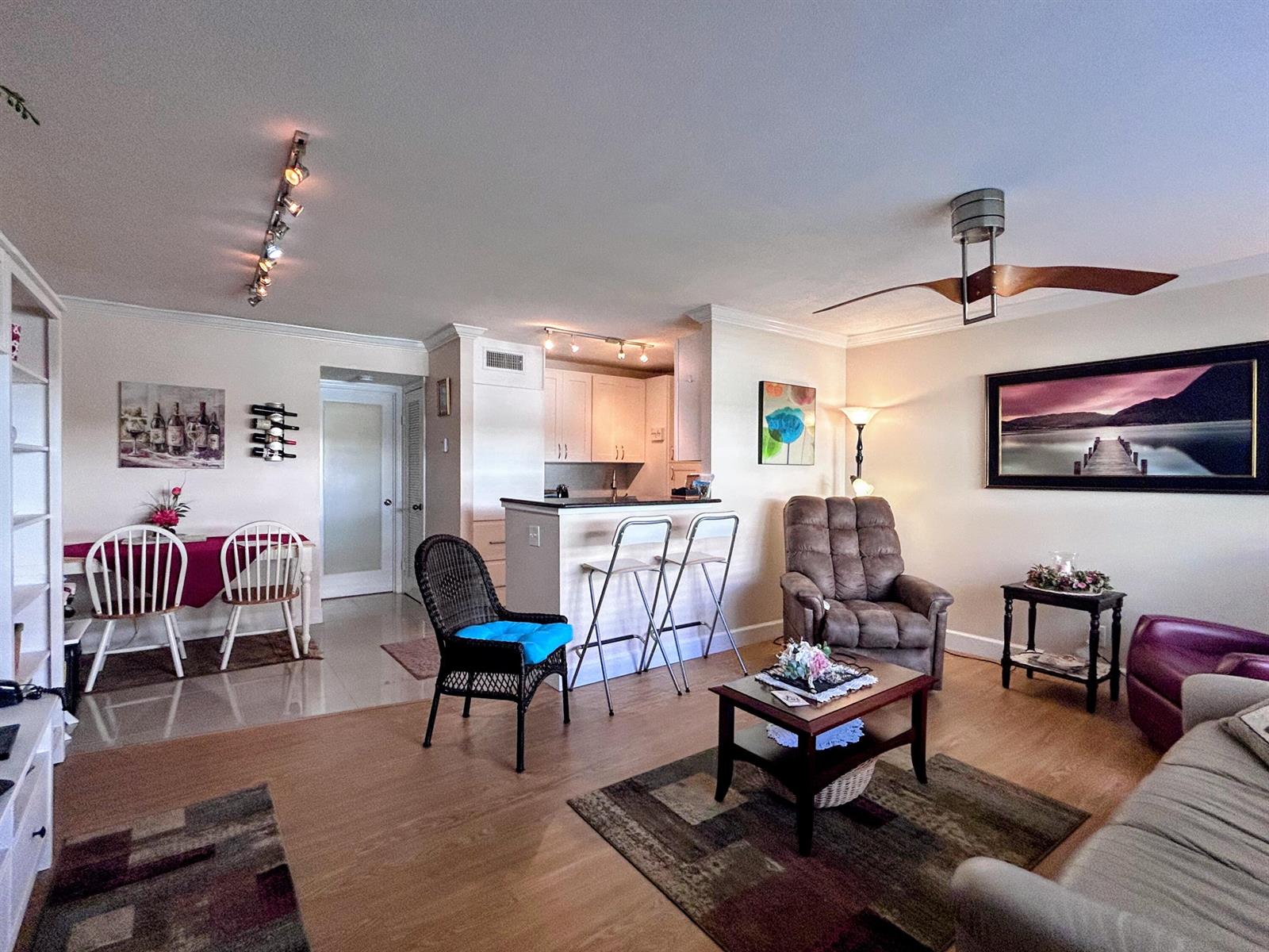 An open-concept living and dining area features light wood flooring, a kitchen island, and furniture — 638 Snug Harbor Drive # E6, Boynton Beach FL 33435, BOYNTON BEACH, FL