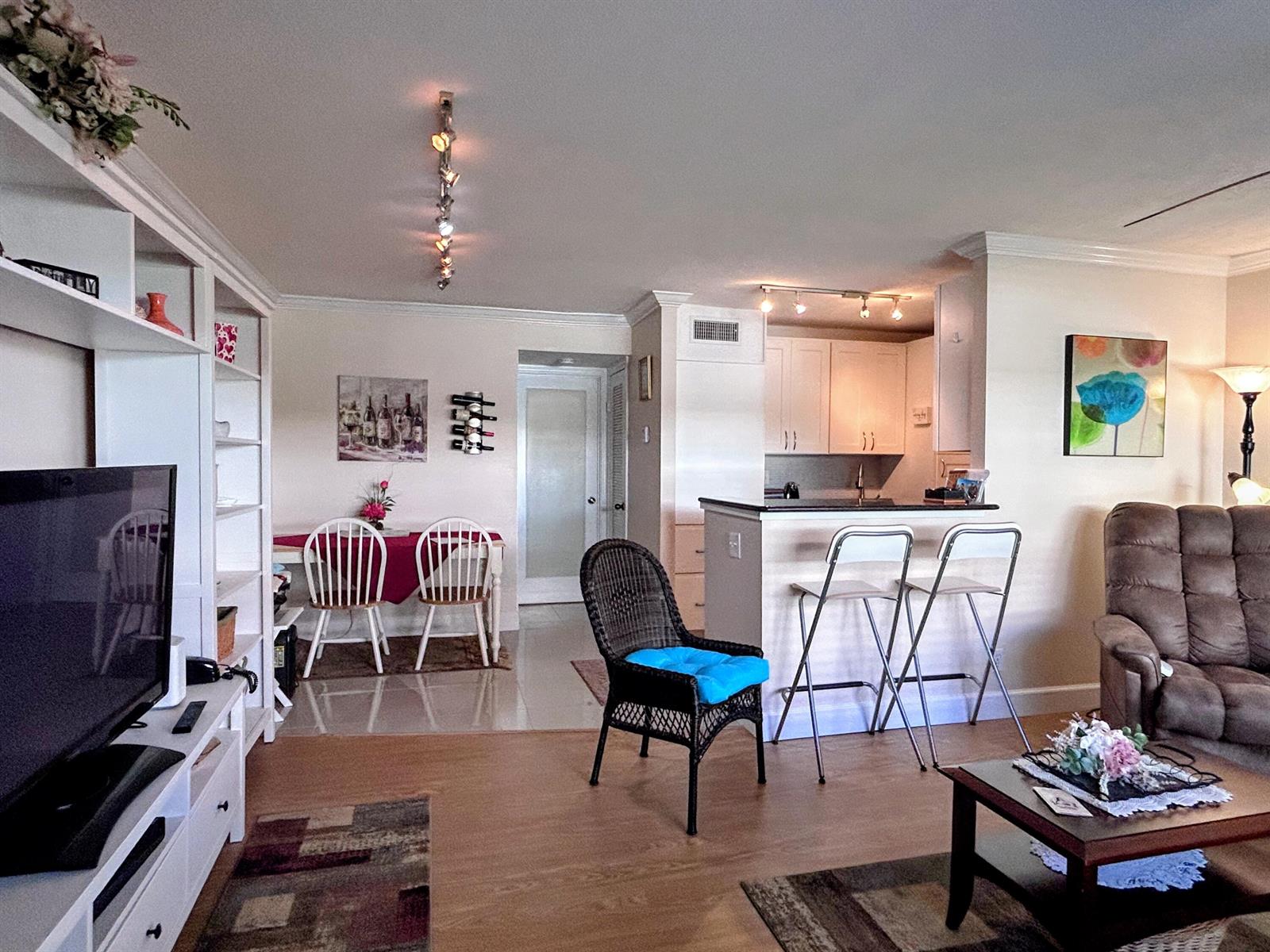 An open-concept living and dining area features light wood flooring, white cabinetry, and a kitchen island — 638 Snug Harbor Drive # E6, Boynton Beach FL 33435, BOYNTON BEACH, FL