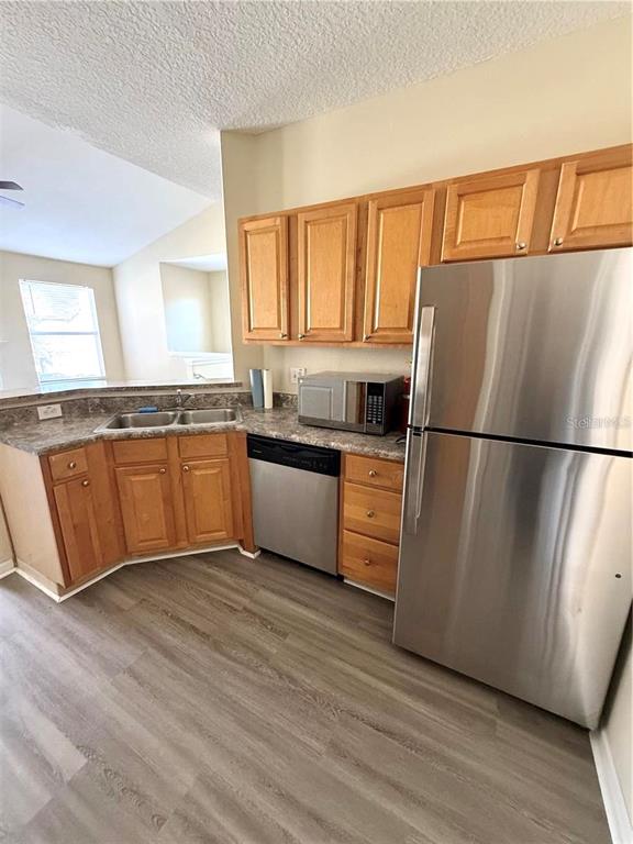 A kitchen features light wood cabinets, stainless steel appliances, and wood-look flooring — 10446 VILLA VIEW CIRCLE, TAMPA, FL