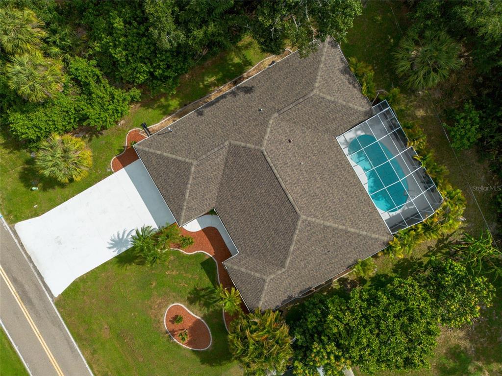 An aerial view shows a house with a shingled roof, pool enclosure, and paved driveway — 1192 ALTON RD, PORT CHARLOTTE, FL