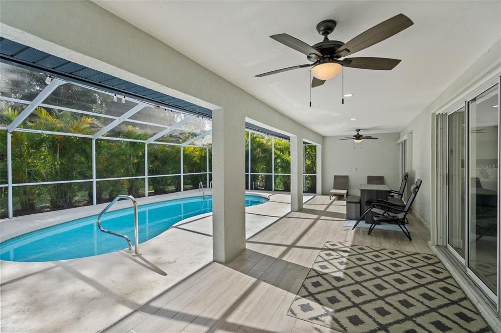 A covered patio features tile flooring, two ceiling fans, and a screened-in swimming pool — 1192 ALTON RD, PORT CHARLOTTE, FL