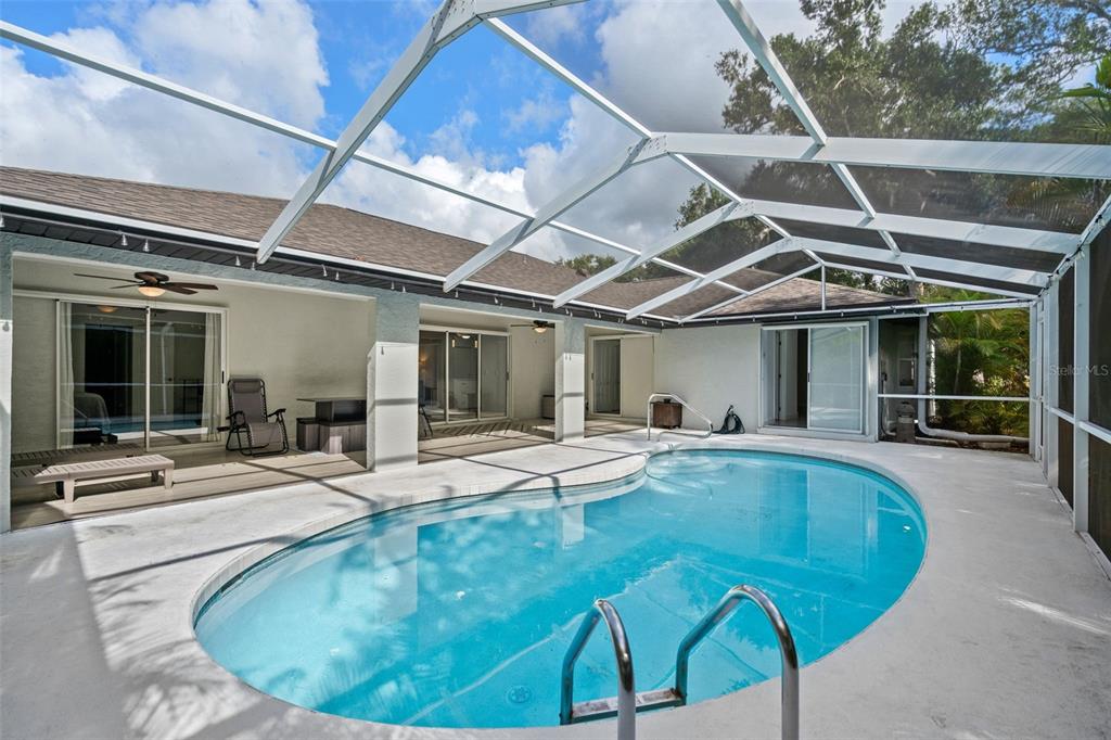 A screened-in patio features a kidney-shaped swimming pool and sliding glass doors to the home — 1192 ALTON RD, PORT CHARLOTTE, FL