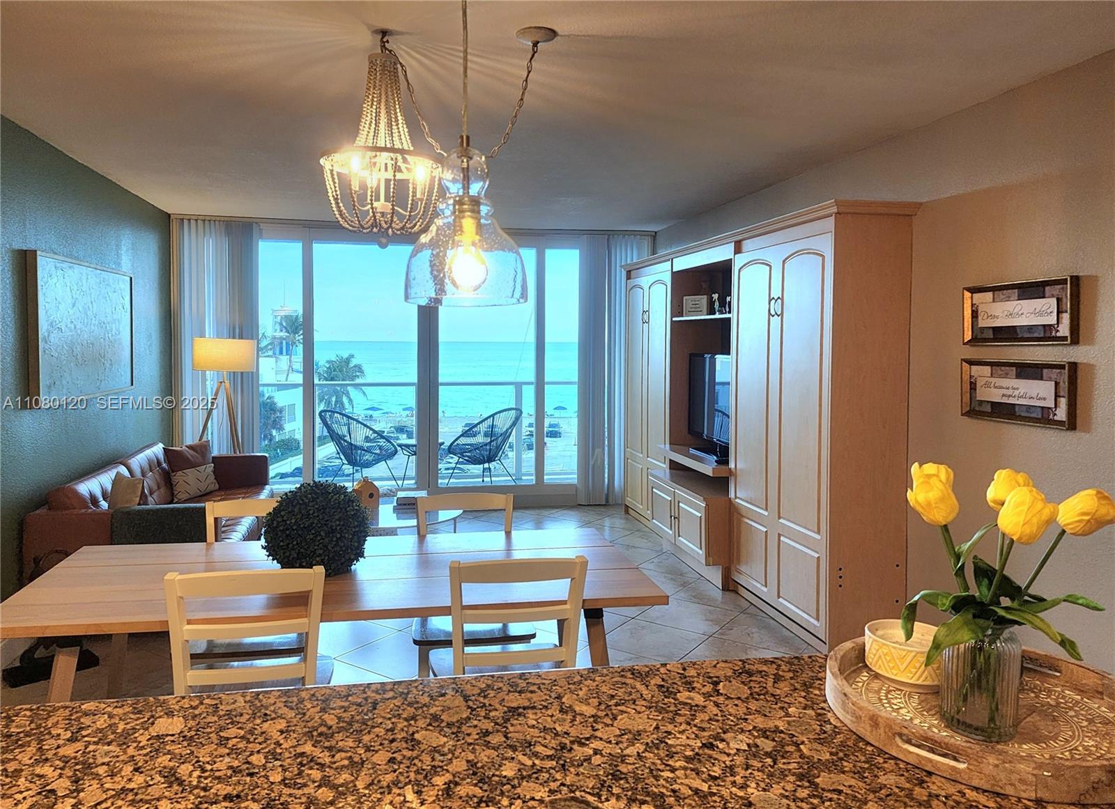 A dining area and living room overlook the ocean through large floor-to-ceiling windows — 3505 S Ocean Dr # 407, Hollywood FL 33019, HOLLYWOOD, FL