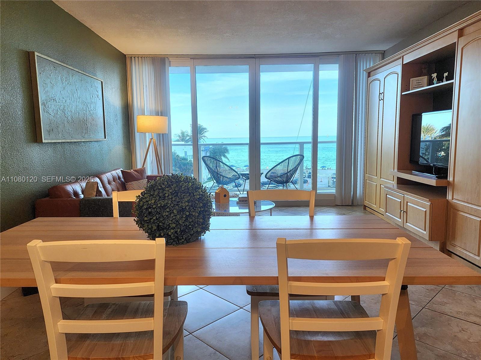 A dining area with a wooden table overlooks a balcony and the ocean beyond — 3505 S Ocean Dr # 407, Hollywood FL 33019, HOLLYWOOD, FL