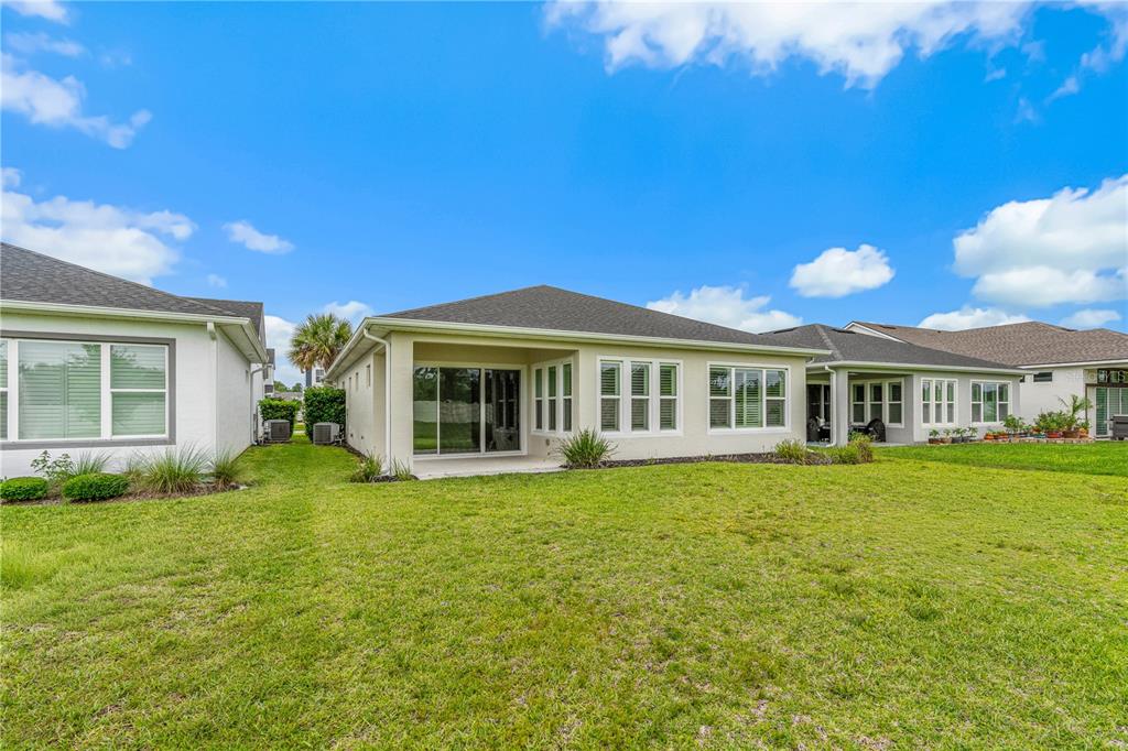The backyard view shows the rear exterior of a single-story house with a covered patio — 6243 WOODHAVEN VILLAGE DRIVE, PORT ORANGE, FL