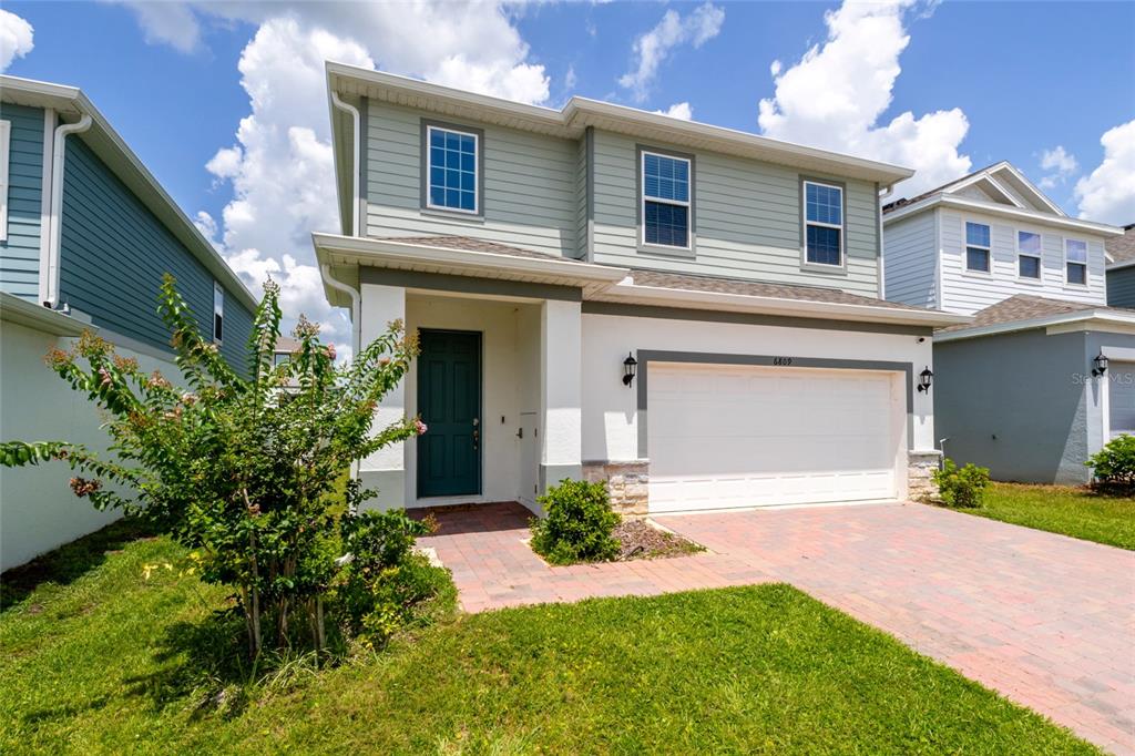 A two-story house with light green siding, a white stucco base, and a two-car garage — 6809 SERPENT HAWK LANE, HOWEY IN THE HILLS, FL
