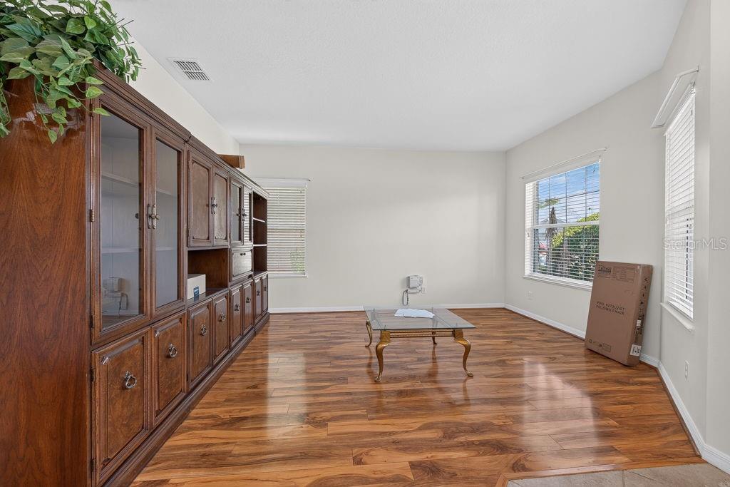 A room with wood-look flooring, a large wooden wall unit, and a glass coffee table — 3614 PLYMOUTH DRIVE, WINTER HAVEN, FL