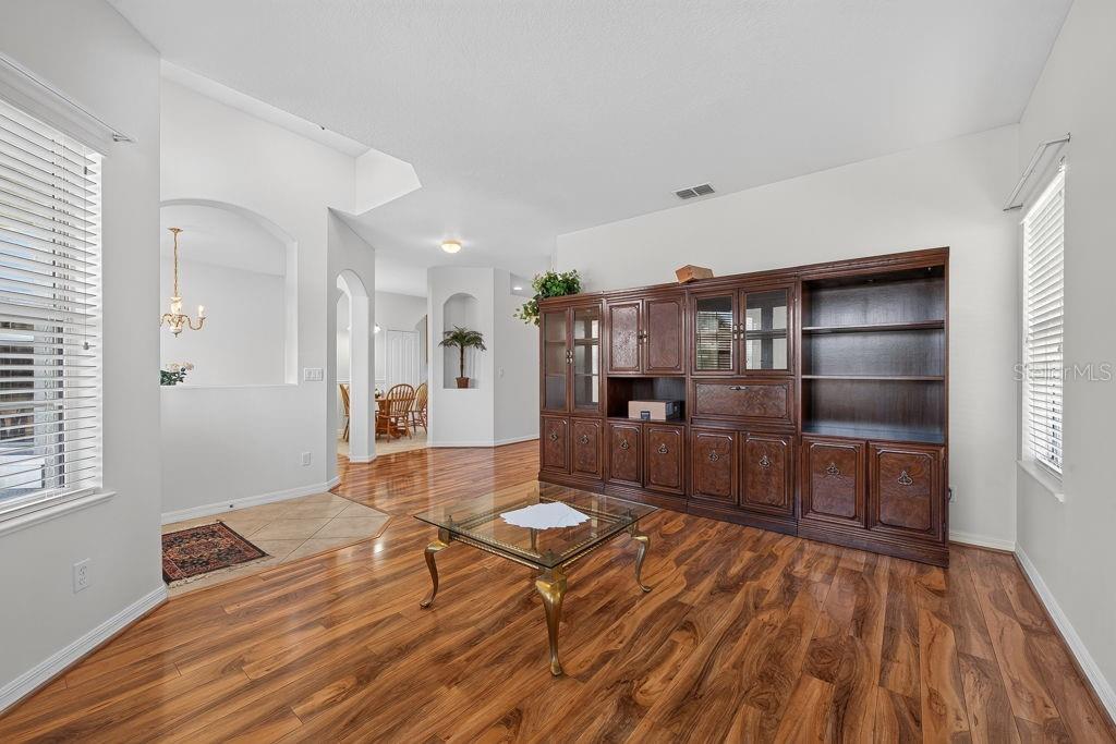 A living room features wood-look flooring, a large dark wood wall unit, and a glass table — 3614 PLYMOUTH DRIVE, WINTER HAVEN, FL