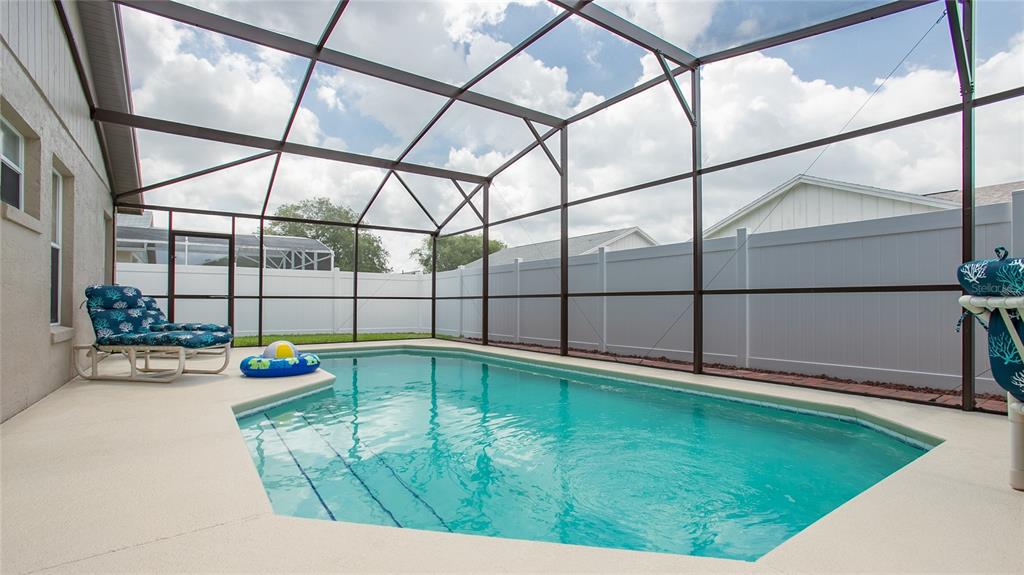 A screened-in swimming pool with a concrete deck sits inside a fenced backyard — 7802 LAUREL OAK LANE, KISSIMMEE, FL