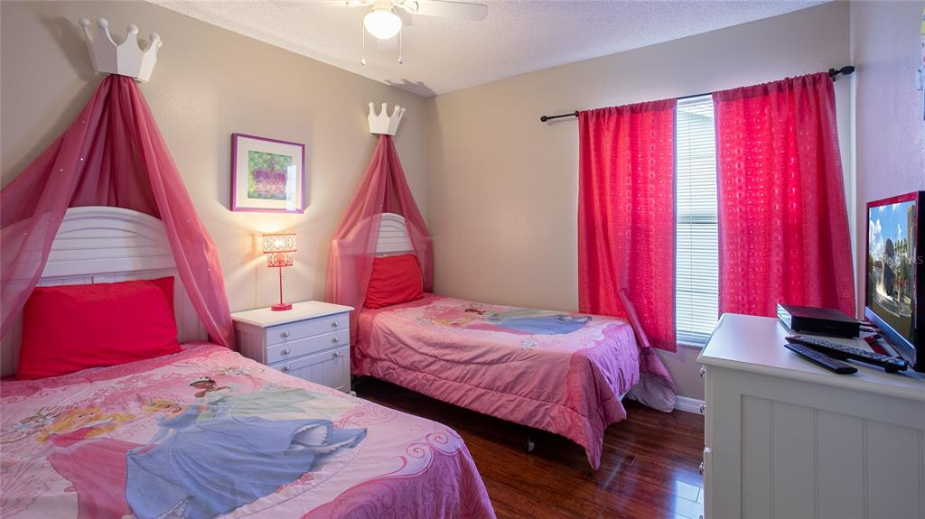 A bedroom features two twin beds with pink princess-themed bedding and crown-shaped wall canopies — 7802 LAUREL OAK LANE, KISSIMMEE, FL