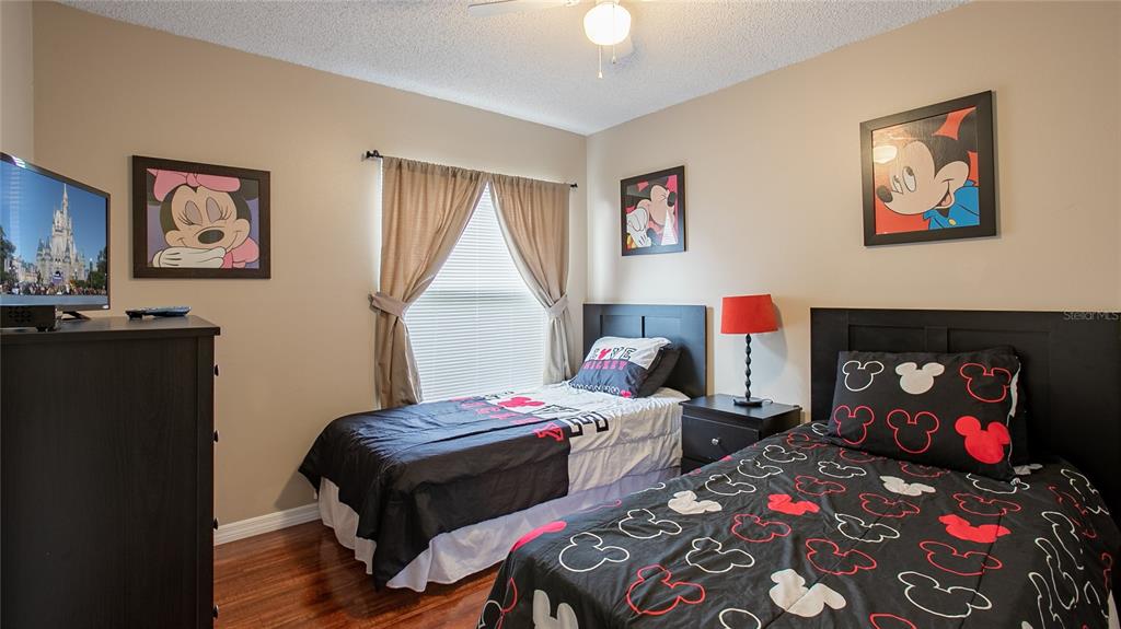 A bedroom features two twin beds, Mickey Mouse decor, and a television on a dresser — 7802 LAUREL OAK LANE, KISSIMMEE, FL