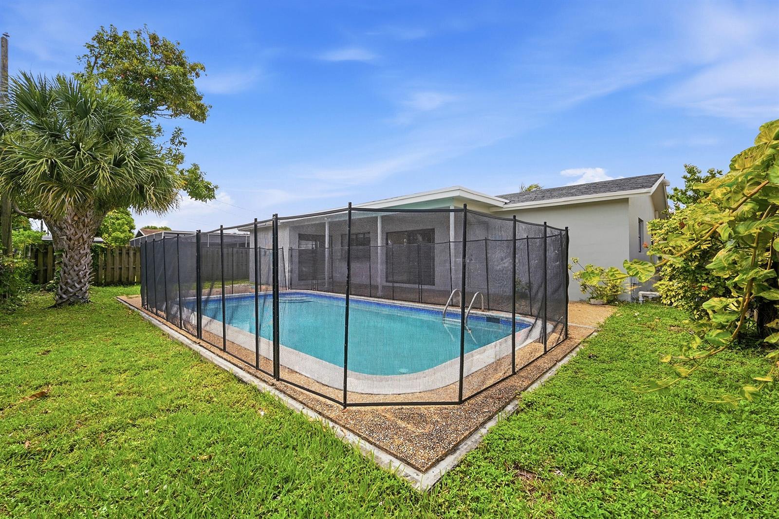 A backyard swimming pool is enclosed by a black mesh safety fence on a patio — 9671 NW 24th Street, Sunrise FL 33322, SUNRISE, FL