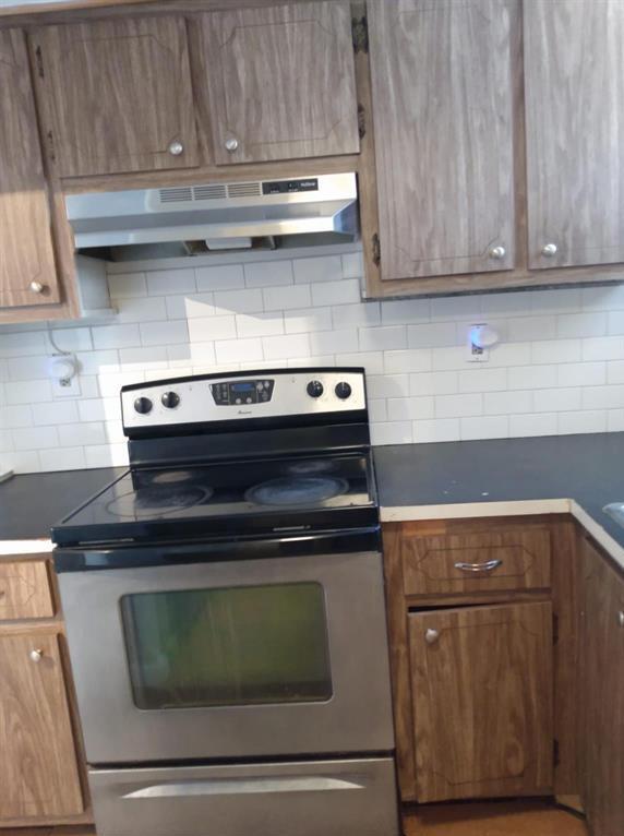 A kitchen features wood cabinets, a stainless steel stove, and a white subway tile backsplash — 8001 Crespi Boulevard # 5c, Miami Beach FL 33141, MIAMI BEACH, FL