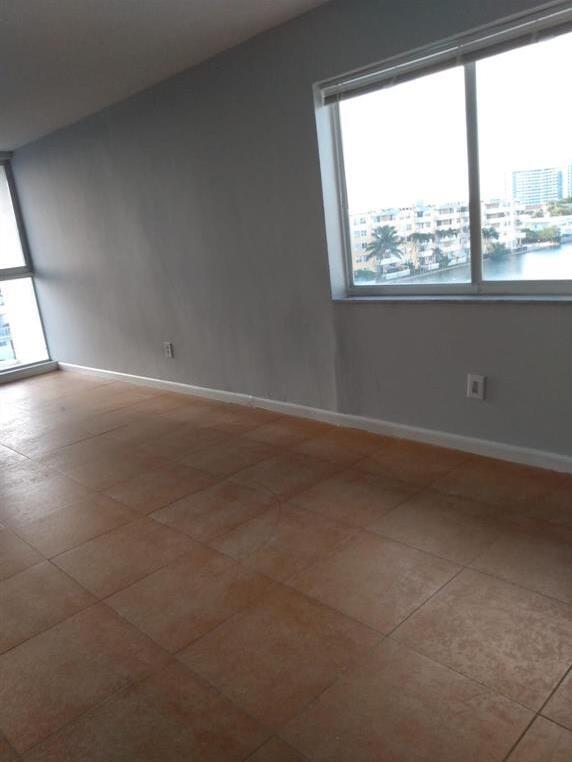 An empty room with light gray walls, tan tile flooring, and a large window view — 8001 Crespi Boulevard # 5c, Miami Beach FL 33141, MIAMI BEACH, FL