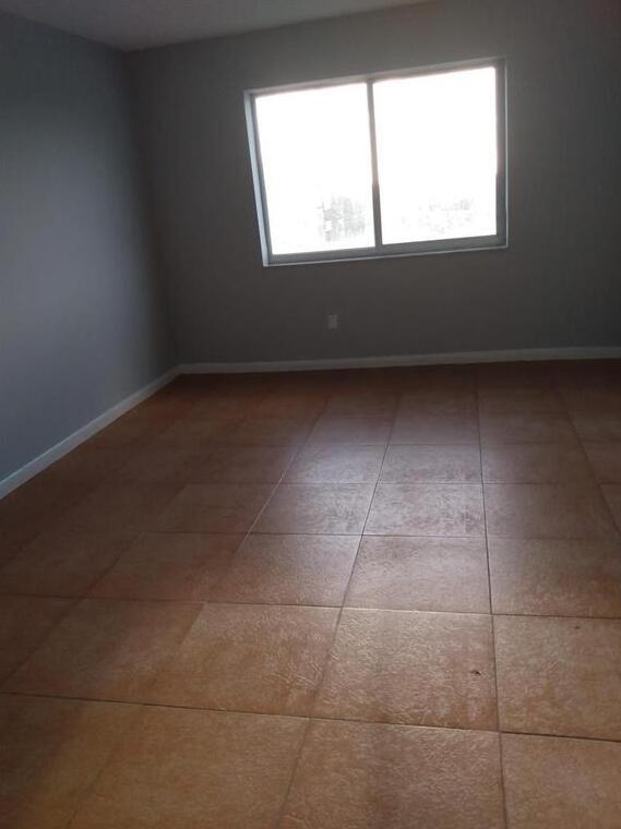 An empty room with grey walls, a single window, and brown tiled flooring — 8001 Crespi Boulevard # 5c, Miami Beach FL 33141, MIAMI BEACH, FL