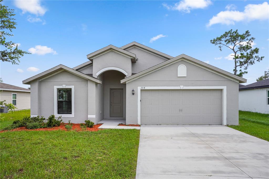 A single-story gray house with a two-car garage and a front entrance under an arch — 204 HYACINTH COURT, POINCIANA, FL
