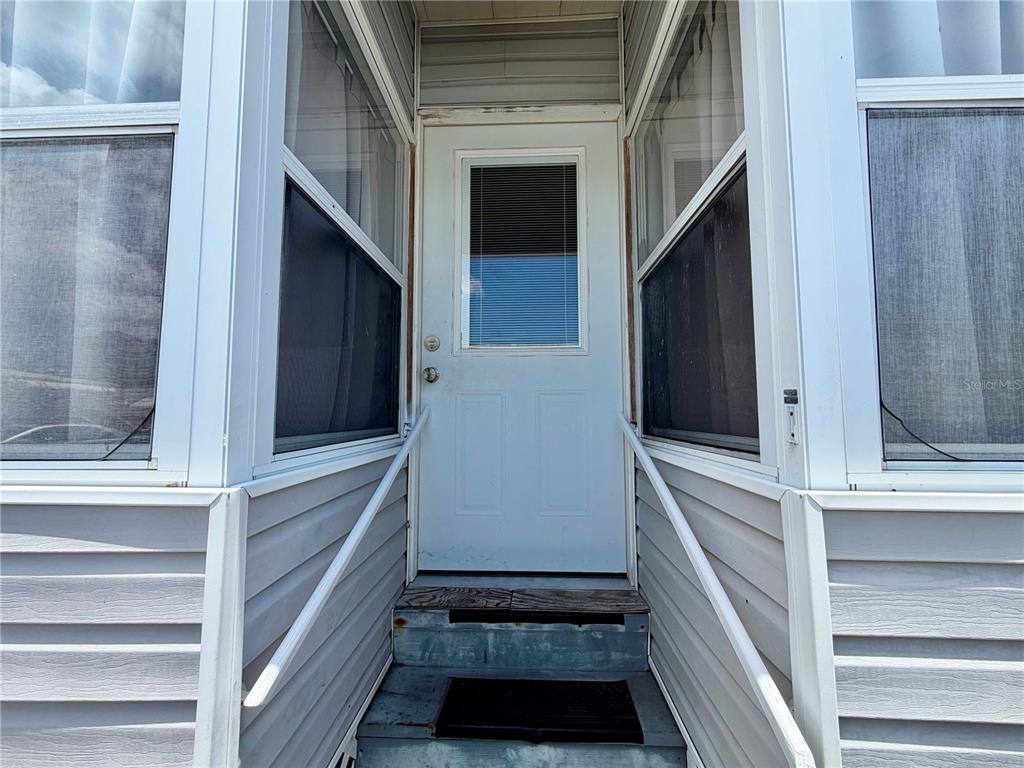 A white exterior door with a window is centered between two screened-in porch sections — 916 51ST AVENUE PLAZA W, BRADENTON, FL