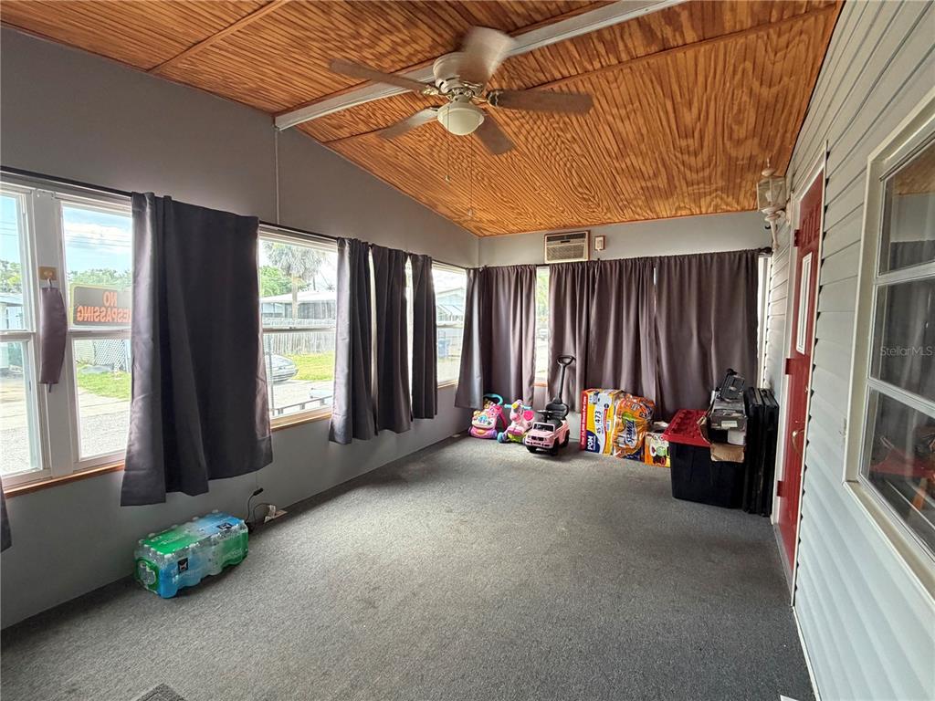 A sunroom with gray carpet, wood-paneled ceiling, ceiling fan, and large windows with gray curtains — 916 51ST AVENUE PLAZA W, BRADENTON, FL