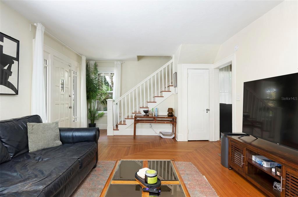 A living room features hardwood floors, a staircase, a black leather sofa, and a television — 540 11TH AVENUE N, ST PETERSBURG, FL