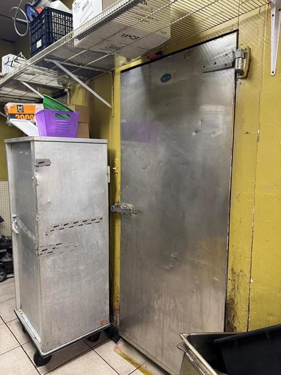A metal door to a walk-in cooler stands next to a tall, rolling metal cabinet — 131 BUENAVENTURA BOULEVARD UNIT 1A, KISSIMMEE, FL