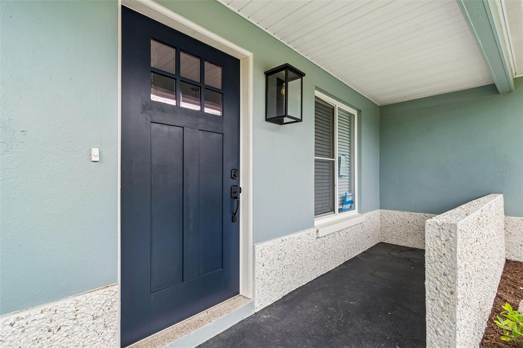 A dark blue front door with a window sits on a porch with textured siding — 403 DRIFTWOOD DRIVE W, PALM HARBOR, FL